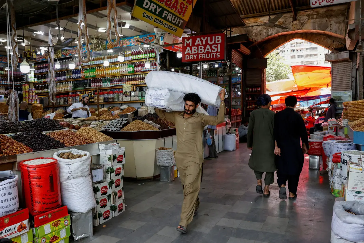 FILE PHOTO: Man walks with sacks of supplies on his shoulder to deliver to a nearby shop at a market in Karachi, Pakistan