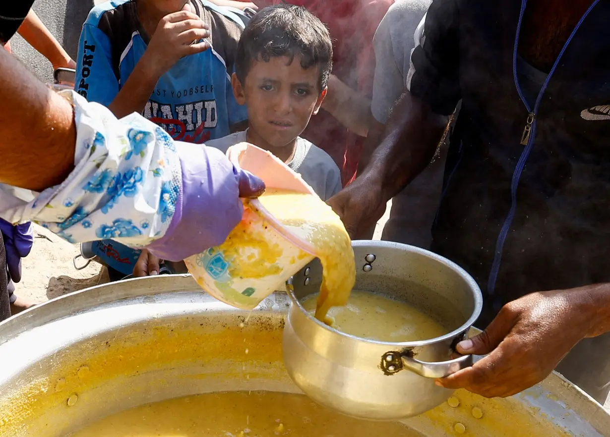 Palestinians gather to receive food cooked by a charity kitchen, in Khan Younis