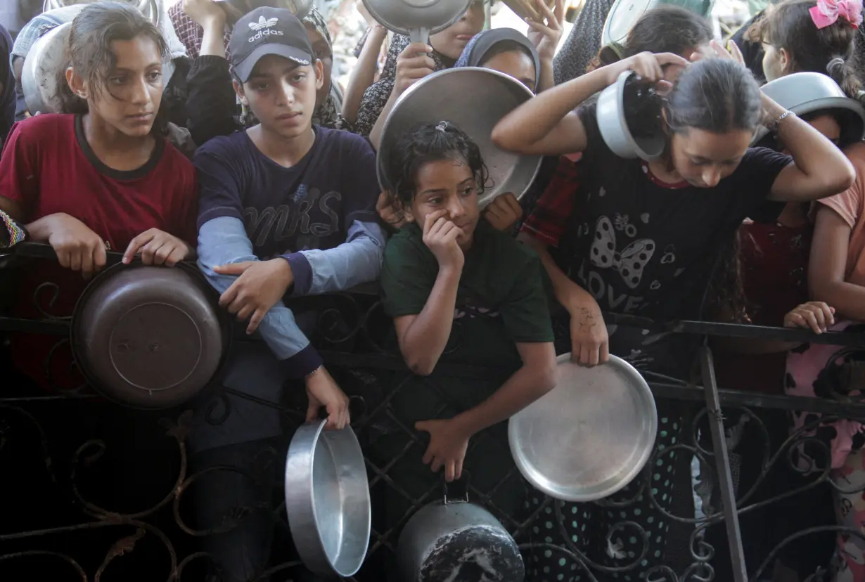 Palestinians wait to receive food cooked by a charity kitchen in the northern Gaza Strip