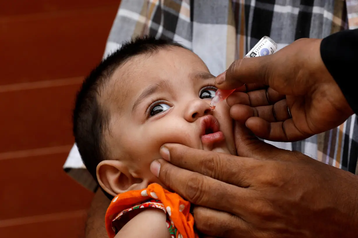 A girl receives polio vaccine drops, during an anti-polio campaign, in a low-income neighborhood, in Karachi