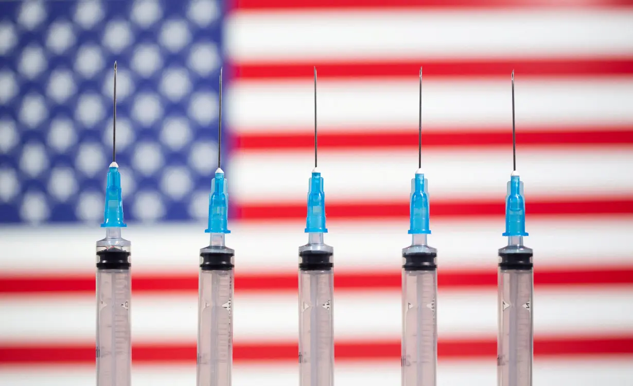 FILE PHOTO: Syringes are seen in front of a displayed U.S. flag in this illustration