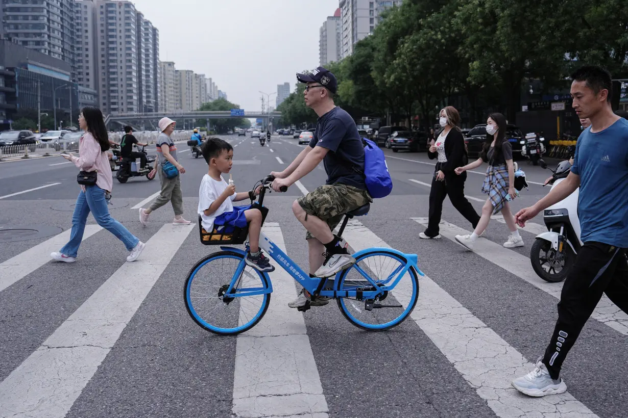 Person rides a bicycle with a child sitting in the basket in Beijing