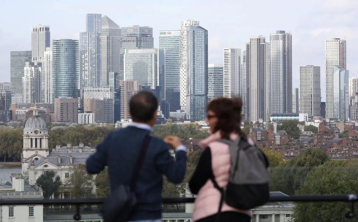 People look out towards the Canary Wharf financial district from Greenwich Park, in London