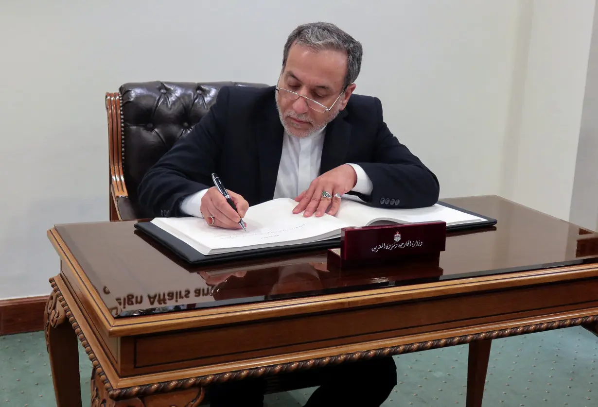 Iran's Foreign Minister Abbas Araqchi signs a guest book at the Jordanian Foreign Ministry in Amman