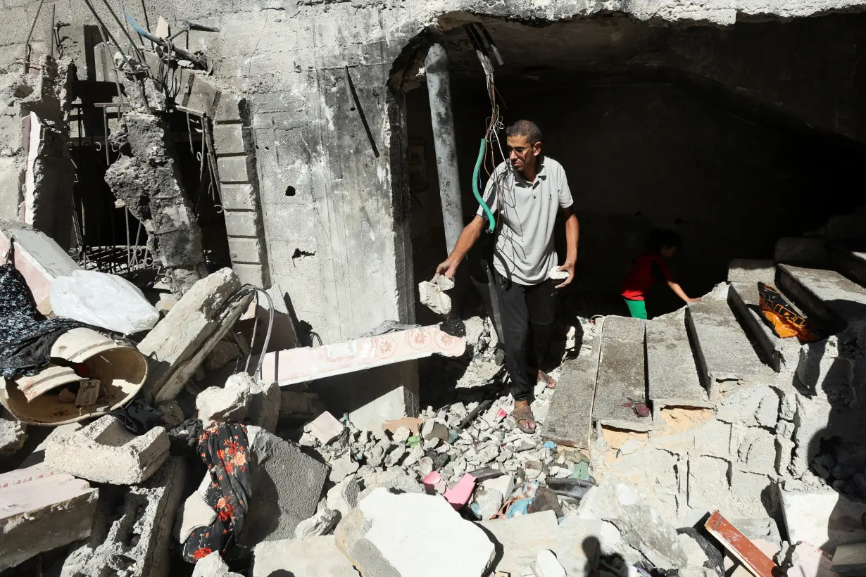 Palestinians inspect the site of an Israeli strike on a house in Al Maghazi refugee camp in the central Gaza Strip