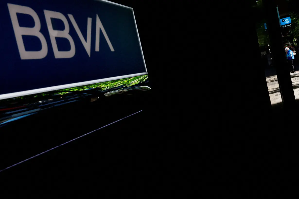 FILE PHOTO: A man uses an ATM machine of Spain's Sabadell bank near a branch of Spain's BBVA bank in Madrid