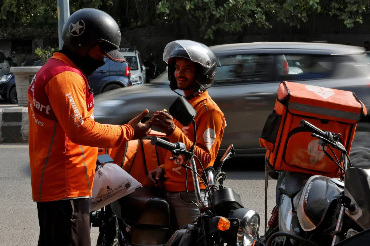 FILE PHOTO: Gig workers prepare to deliver orders outside Swiggy's grocery warehouse, in New Delhi