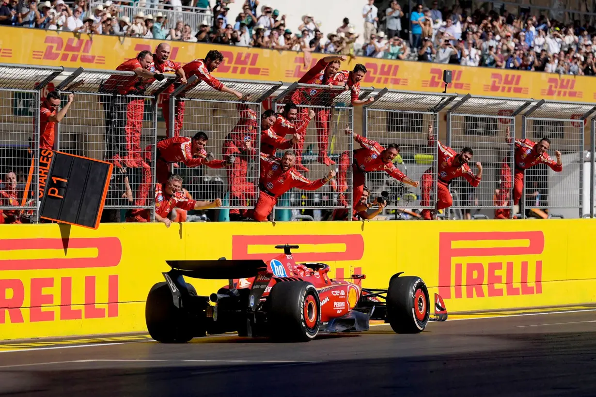 Team members stand along the fence celebrating as Leclerc wins the US Grand Prix.