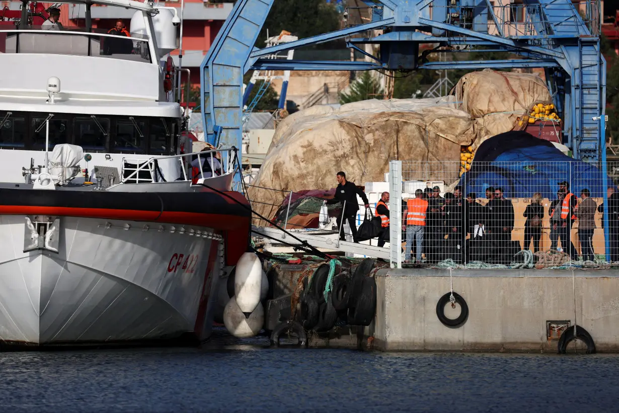 FILE PHOTO: Migrants board an Italian coast guard vessel in Shengjin, Albania