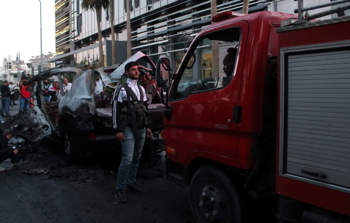 Security forces member stands near the wreckage of car in the Mazzeh area of Damascus