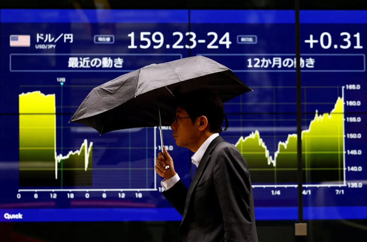 A man walks past an electronic screen displaying the current Japanese Yen exchange rate against the U.S. dollar and the graph showing its recent movement in Tokyo