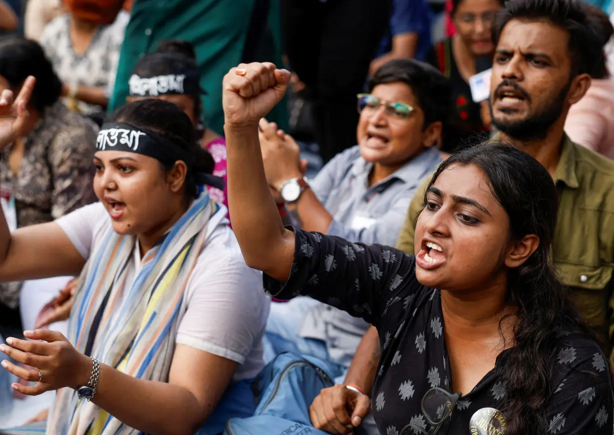 Medics sit and chant slogans as they attend a protest condemning the rape and murder of a trainee medic at a government-run hospital, in Kolkata