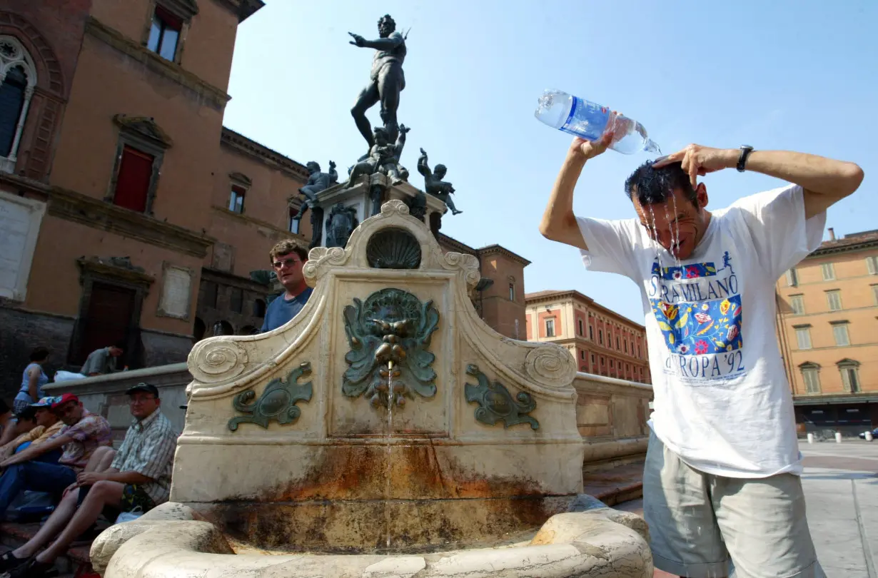 A tourist refreshes himself in front of the famous Neptune fountain in Bologna, central Italy, Augus..