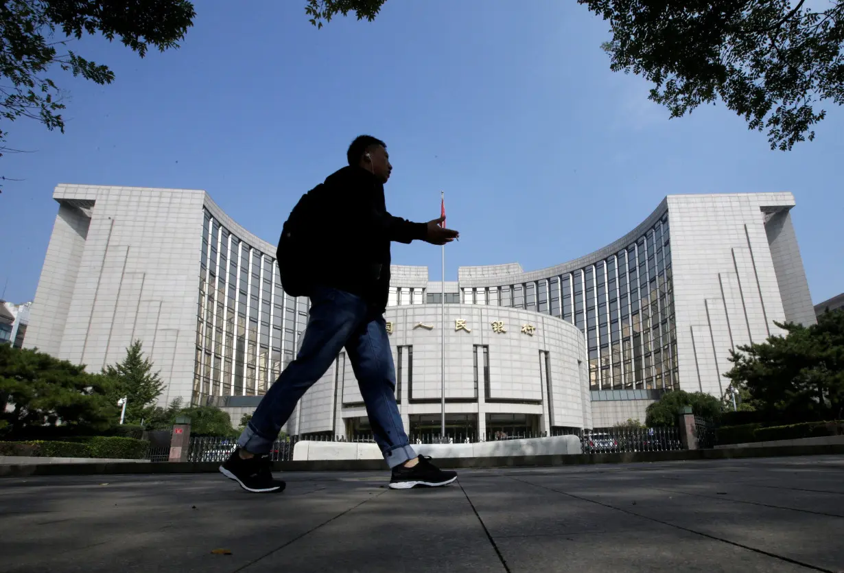 FILE PHOTO: A man walks past the headquarters of the PBOC, the central bank, in Beijing