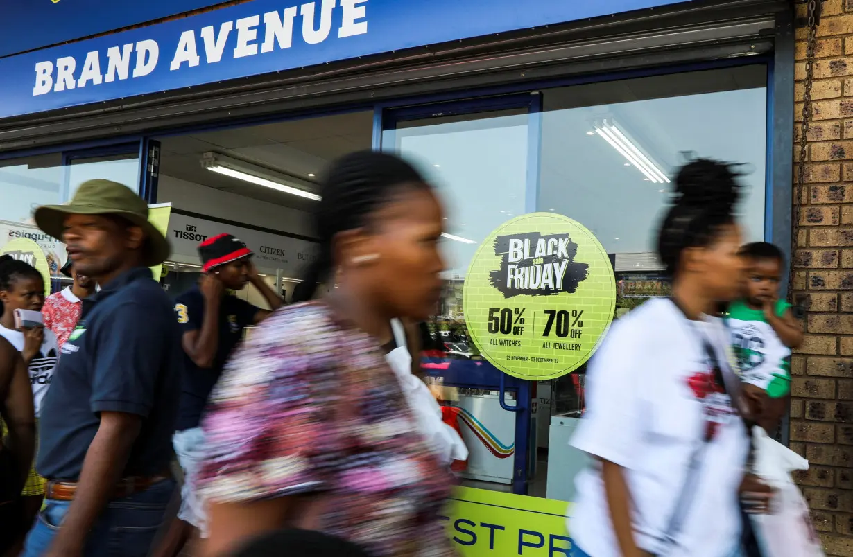 Shoppers walk past a shop window displaying Black Friday signage at Woodmead Value Mart, in Johannesburg