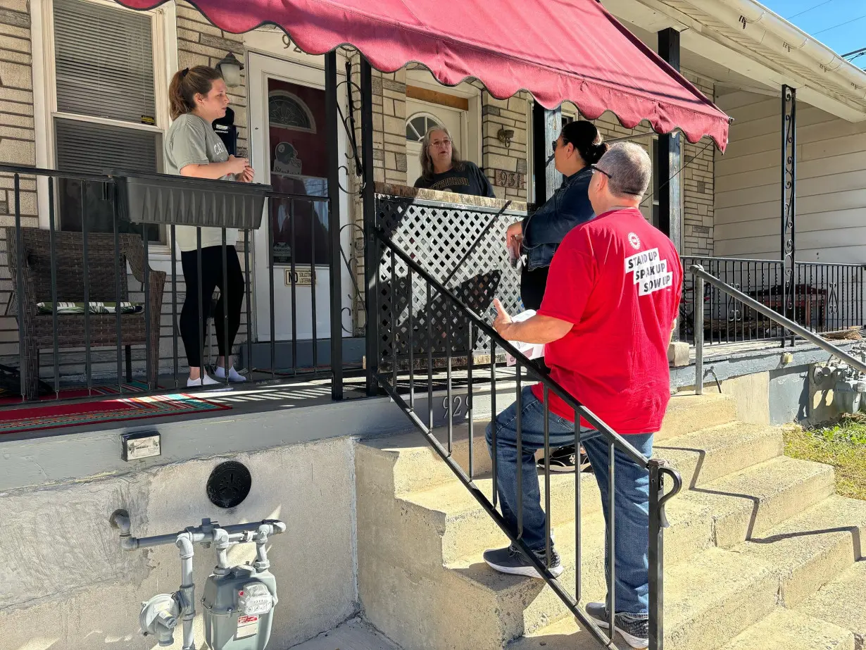 Angela Ferritto, president of Pennsylvania's AFL-CIO, and Jim Hutchinson, UAW Local 644 president, speak to Cheyenne and Cindy Lazarus as they knock doors for Democrats around Allentown, Pennsylvania, on October 20.