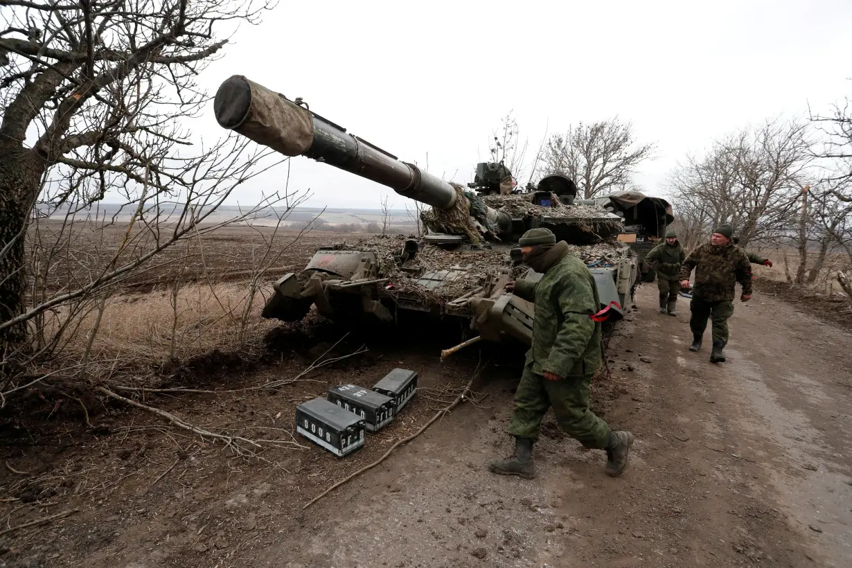 FILE PHOTO: Pro-Russian separatists walk near a tank in Donetsk region