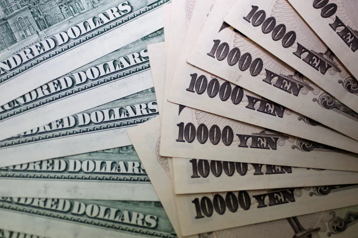 FILE PHOTO: JJapanese 10,000 yen notes are spread out next to U.S. 100 dollar bills at Interbank Inc. money exchange in Tokyo