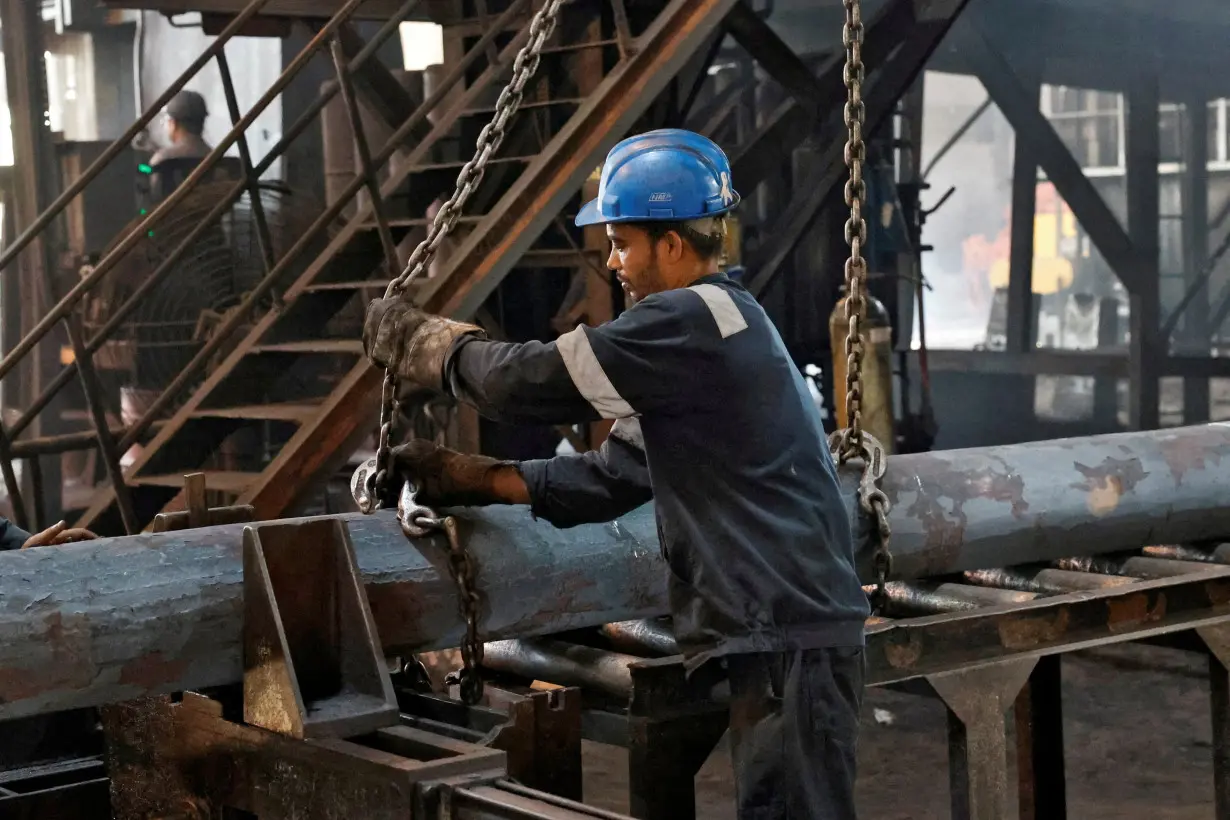 FILE PHOTO: An employee prepares to move a heavy bar of steel inside the ArcVac ForgeCast factory, in Hooghly district