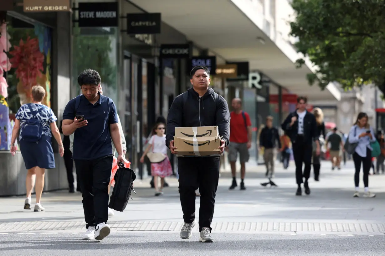 FILE PHOTO: Shoppers walk past retail stores in central London