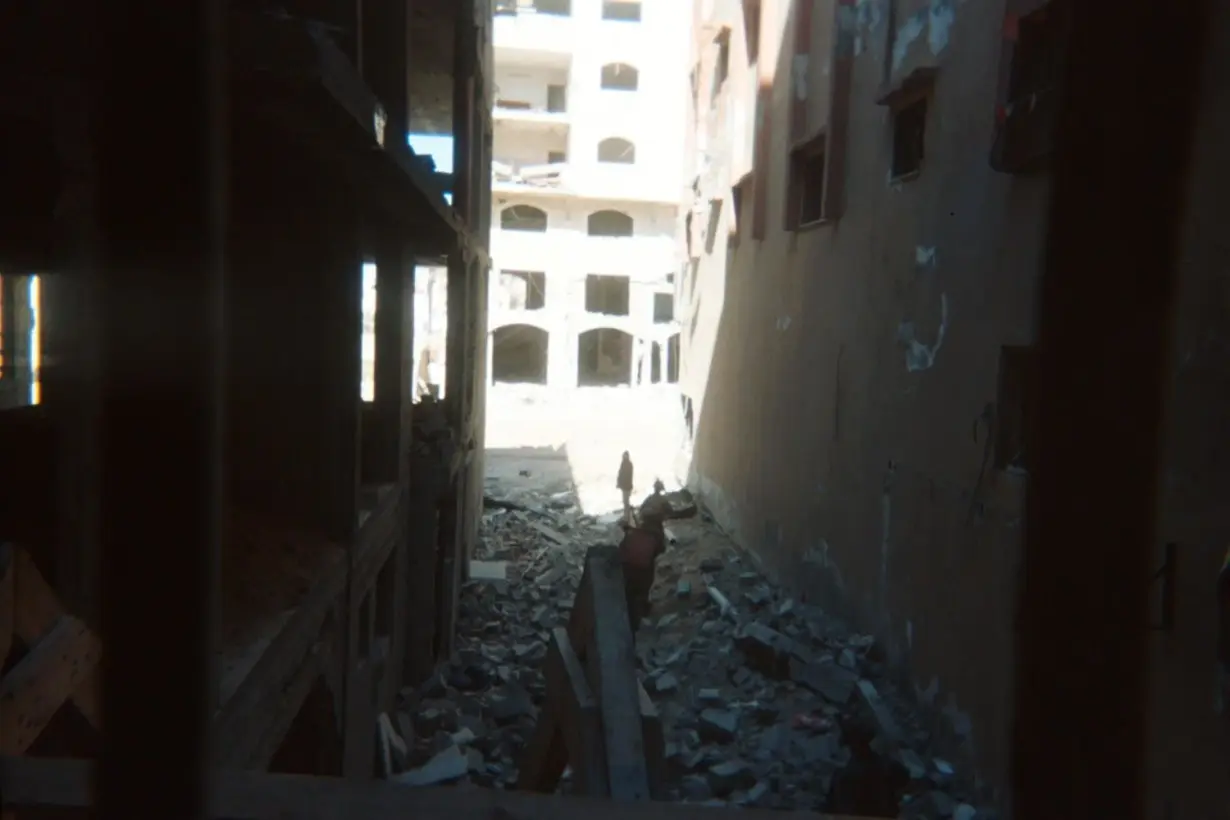 A photograph shows two soldiers urging a Palestinian forward in a scene of devastation in northern Gaza.