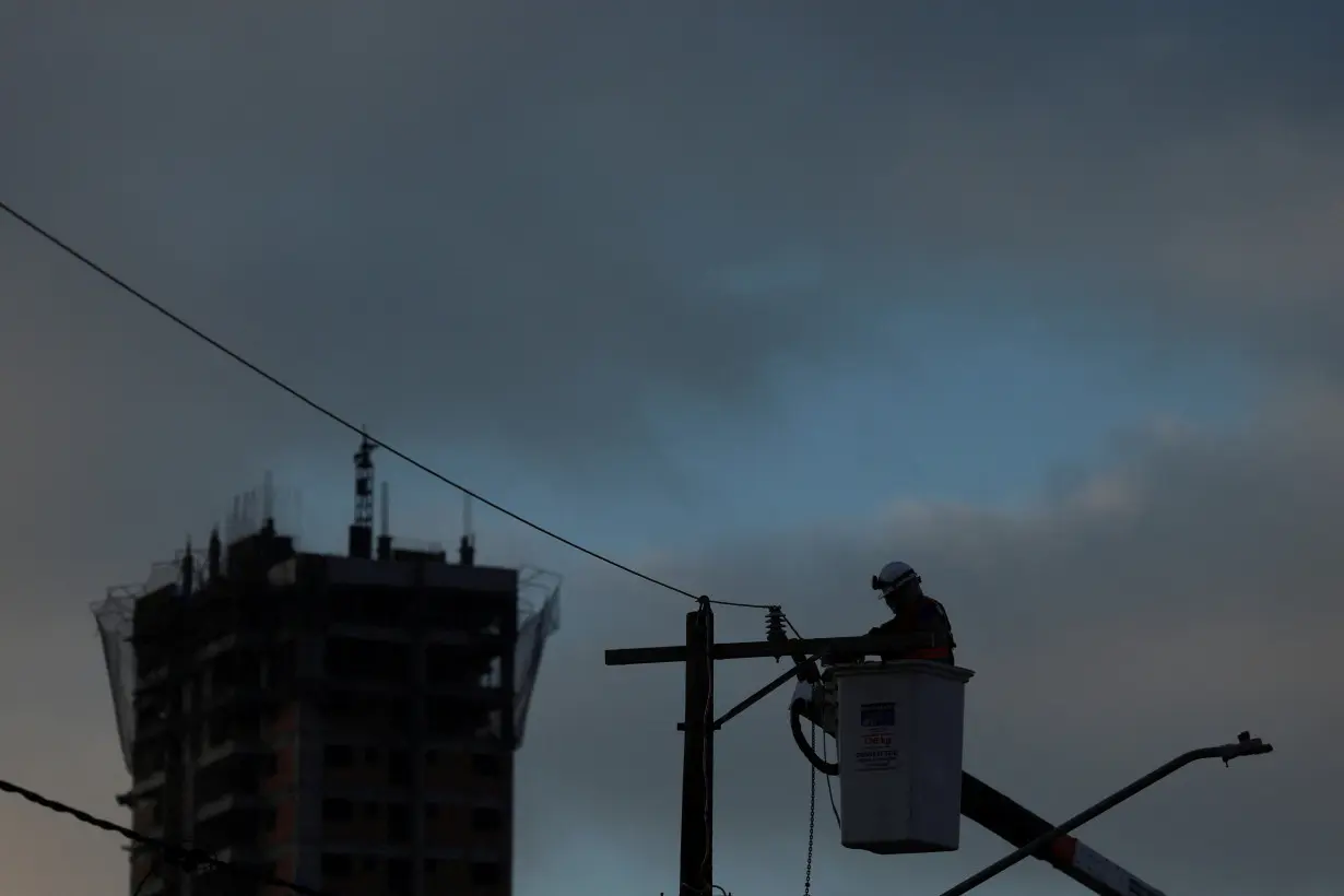 FILE PHOTO: A man works on a pole to restore electricity in Sao Paulo