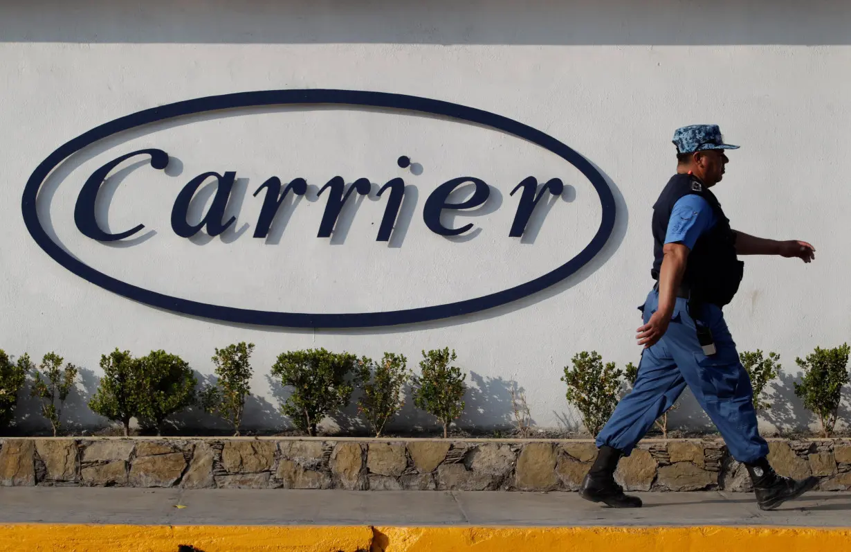 Private security guard walks past a logo of Carrier Corp outside the air conditioner plant, a unit of United Technologies Corp, in Santa Catarina