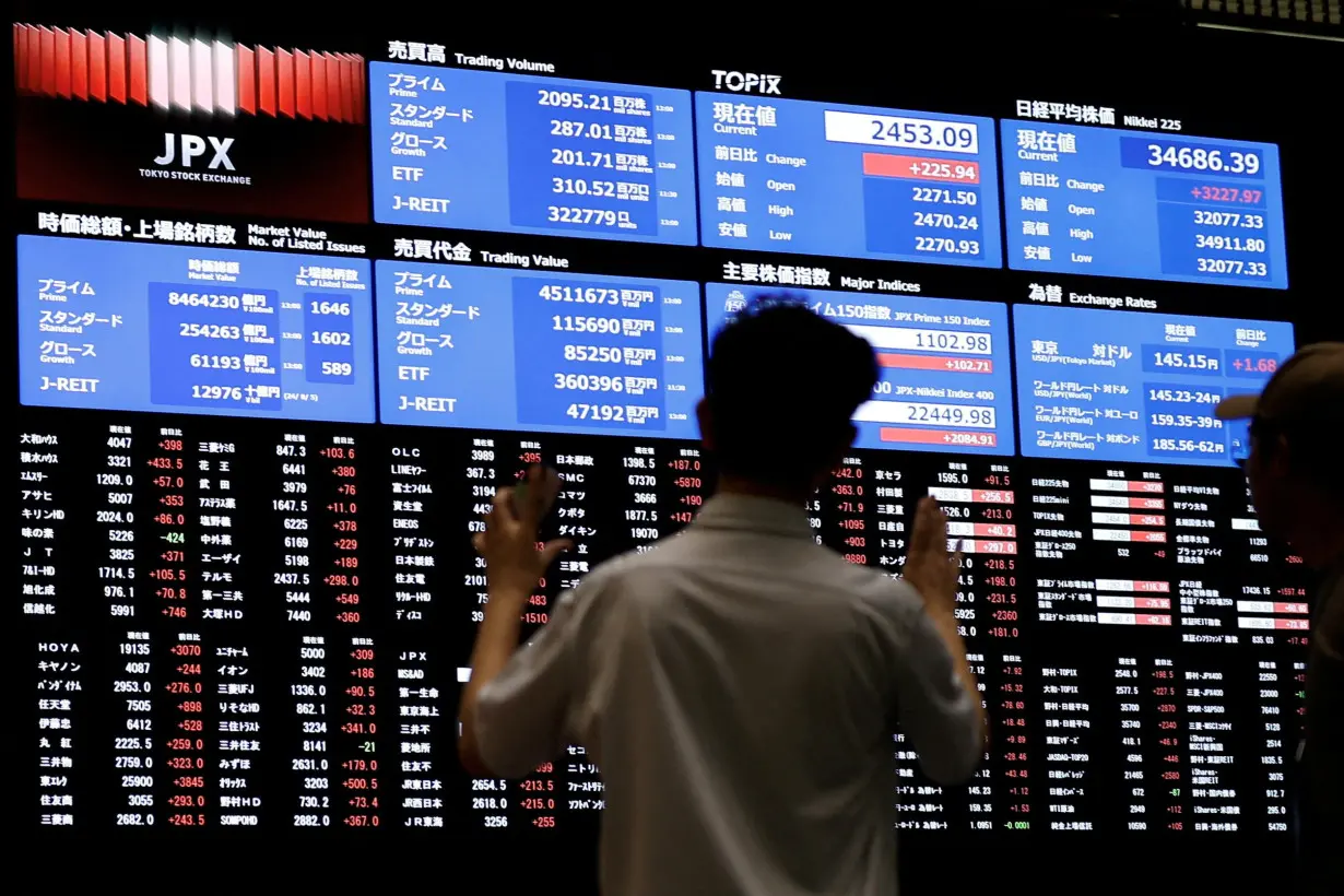 FILE PHOTO: Media members observe the stock quotation board at Tokyo Stock Exchange in Tokyo