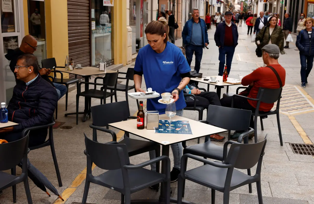 A waitress clears a table at the terrace of a bar in downtown Ronda