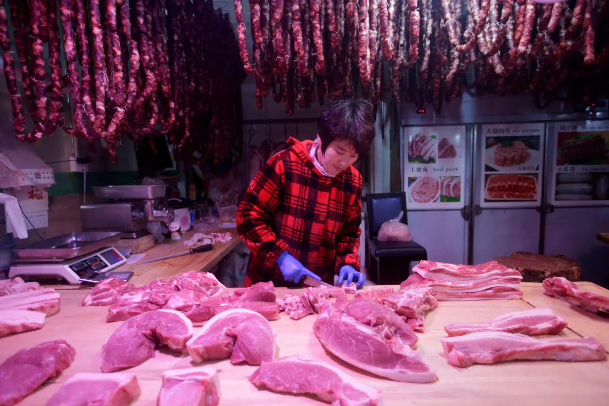 FILE PHOTO: A vendor cuts meat at a market in Beijing