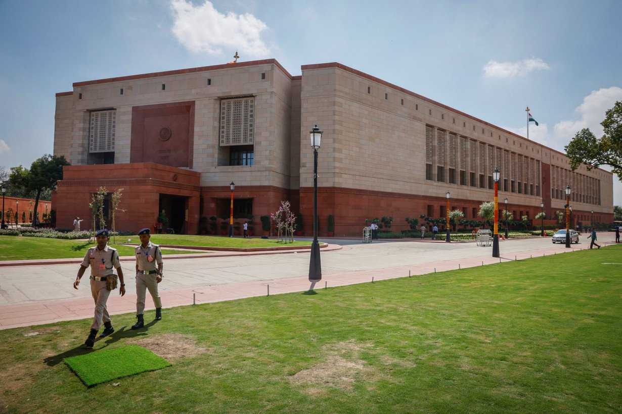 Police officers walk in front of India's new parliament building a day before its inauguration in New Delhi