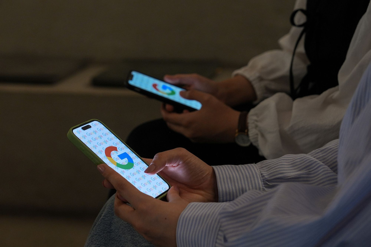 Two women look at their mobile phones displaying the logo of Google in Ankara, Turkiye on September 3.