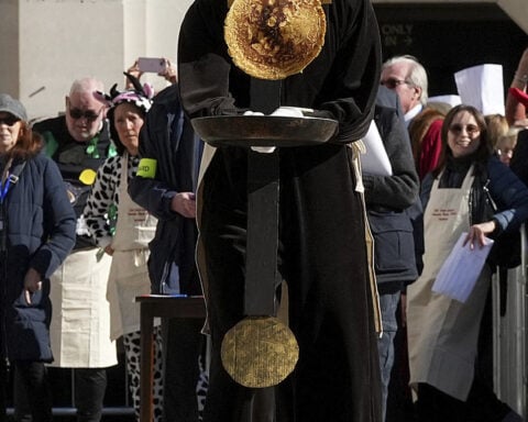 Crowds cheer as runners with frying pans race to mark annual Pancake Day
