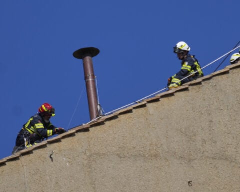 Vatican firefighters install a chimney on the roof of the Sistine Chapel for the papal election