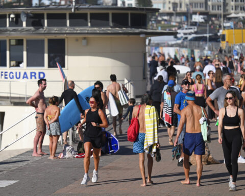 A sunrise crowd gathers at Bondi Beach in solace and defiance after a massacre