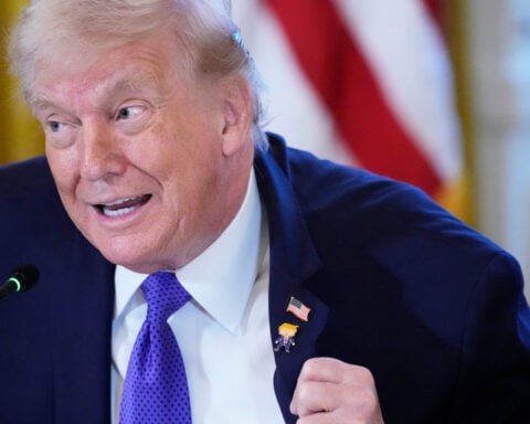 Trump wears a new 'Happy Trump' lapel pin, but insists he's never happy