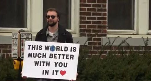 Man spreads positivity and love with motivational signs