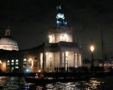 Olympic flame glides on traditional Venetian boats down the Grand Canal