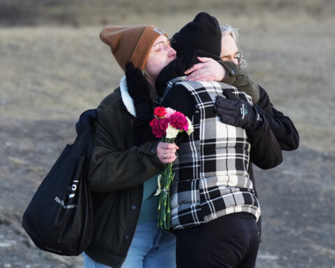 Prime Minister Carney and Canada's main opposition leader hold hands during school shooting vigil
