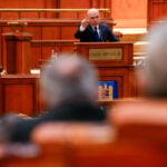 Romania's prime minister fights for survival as no-confidence motion is debated in Parliament