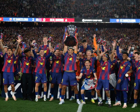 Watched by its grieving coach, Barcelona retains Spanish league title by beating rival Real Madrid