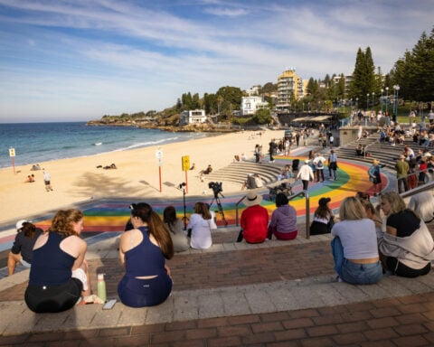 Woman mauled by shark off Sydney beach grabs onto a lifeguard's paddleboard