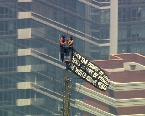 Two people scale to top of Empire State Building and appear to get engaged