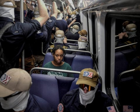 PICTURE AND ITS STORY-Patriot Front members and a solitary woman travel on a DC train