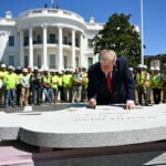 Trump unveils another construction project and signs piece of new helipad during impromptu tour