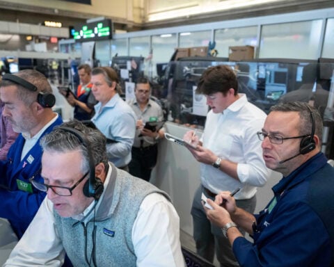 US stocks hover near their latest record in mixed trading on Wall Street